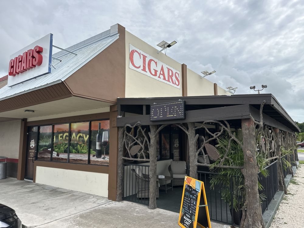 Legacy Cigars Lounge storefront on SE 1st Ave, with the red CIGARS signs and the covered patio